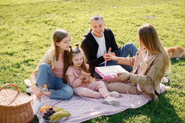 公園でピクニックをしている若い家族とそのコーギー犬
