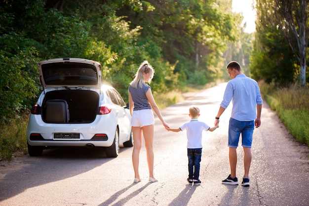 Young family travels by car. Dad, mom and little son take a break from driving a car and walk.