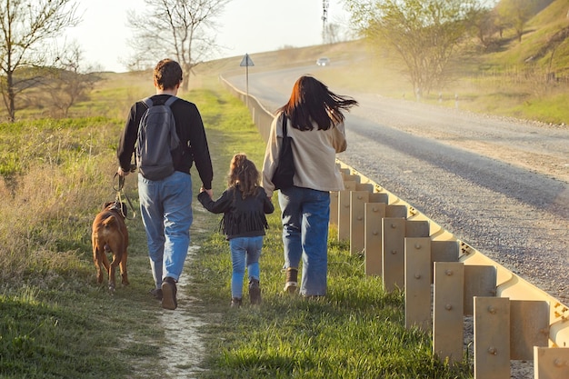 young family on a walk along the road with a dog