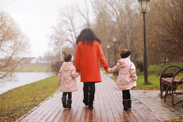 Young family on a walk in the autumn park on a sunny day. Happiness to be together.