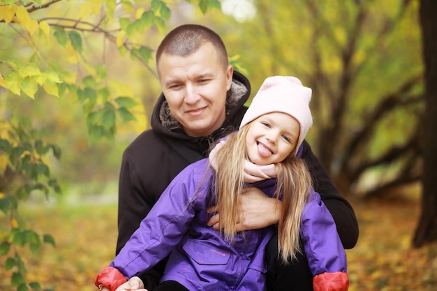 Young family on a walk in the autumn park on a sunny day happiness to be together