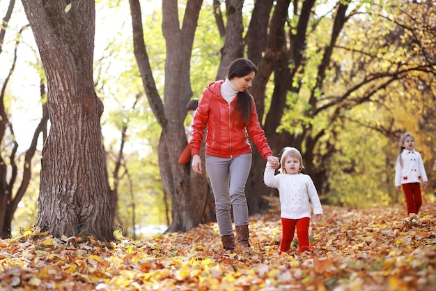 Giovane famiglia in una passeggiata nel parco autunnale in una giornata di sole felicità di stare insieme