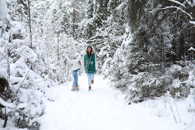 Young family for a walk. Mom and daughter are walking in a winter park.