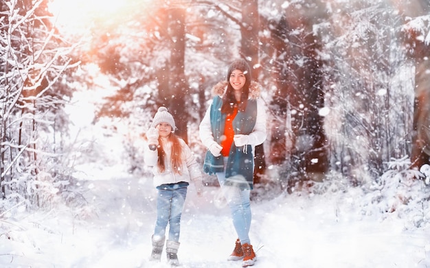 Young family for a walk. Mom and daughter are walking in a winter park.