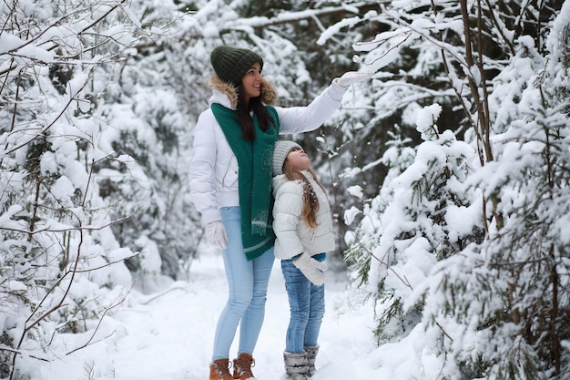 Young family for a walk. Mom and daughter are walking in a winter park.