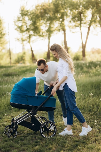 A young family walk in the park in with a toddler in a stroller Happy parents