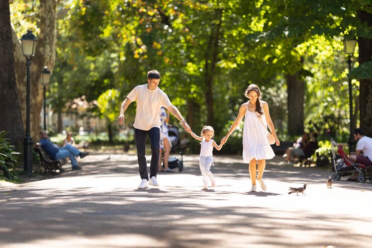 公園の晴れた道を歩く若い家族