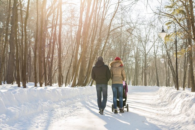 Young family walking with baby stroller in park.