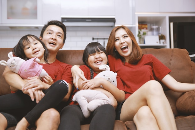 Young family watching TV together at home and having fun together