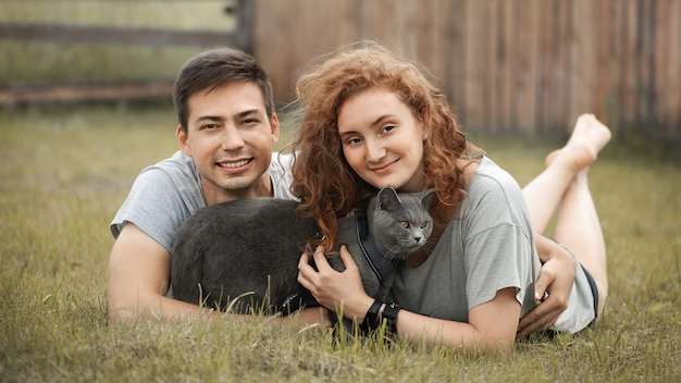 Young family with a cat are resting on the grass