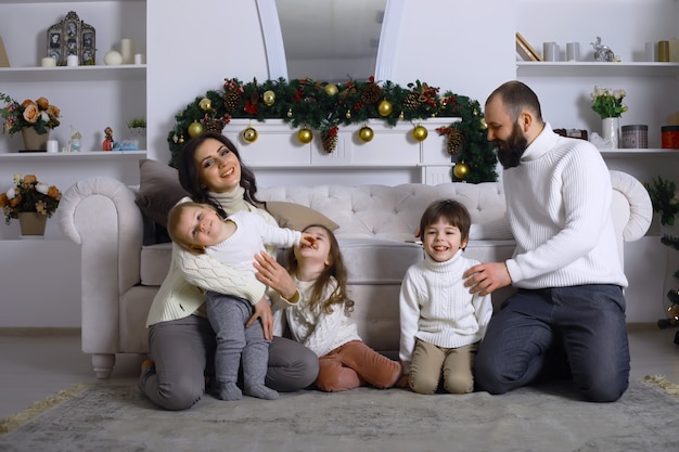 子供連れの若い家族が休日の家を飾ります。大晦日。新年を待っています。