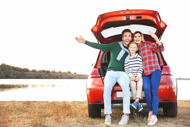 写真 川の近くの車のトランクに座っているかわいい男の子と若い家族