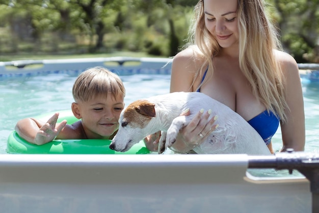 犬と一緒に若い家族が夏の外のフレームプールで泳ぐ裏庭でリラックス