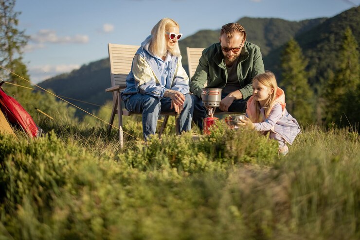Young family with little girl on picnic in the mountains