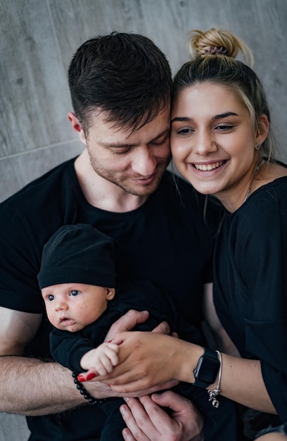 Young family with newborn baby Dad mom and baby dressed in black clothes