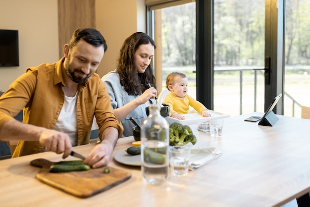 Photo young family with a one year baby boy during a lunch time at home