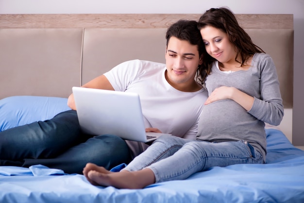 Young family with pregnant wife expecting baby in bed