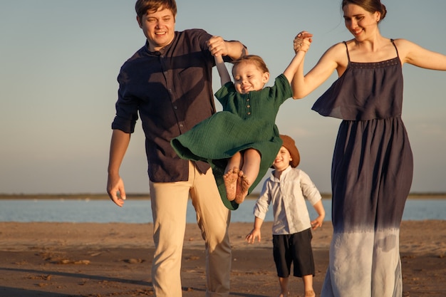 Young family with two children playing on the evening beach.