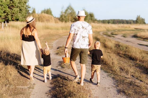 A young family with two children walks in nature outside the city in the summer