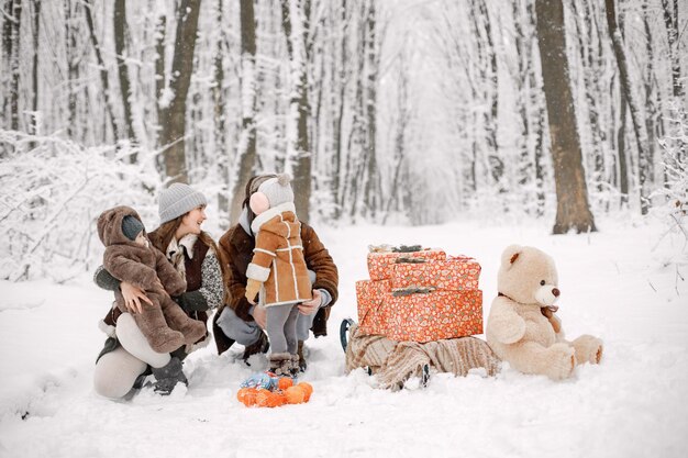 겨울 숲에서 두 아이와 사진을 위해 포즈를 취하는 젊은 가족