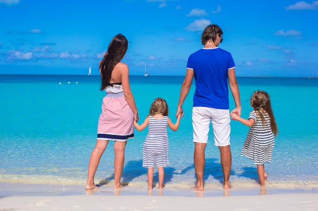 Молодая семья с двумя детьми на тропическом белом пляже