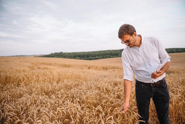 Young farmer engineer standing on wheat field