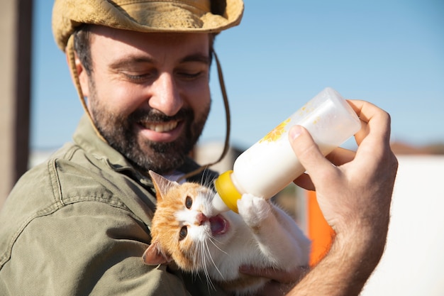 写真 農場でボトルから猫のミルクを与えている若い農家