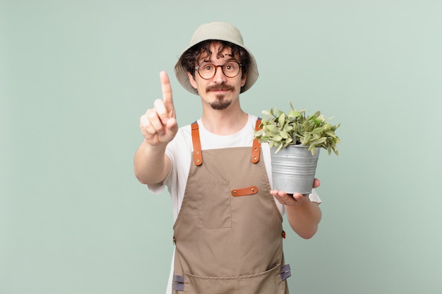 Young farmer man smiling and looking friendly, showing number one