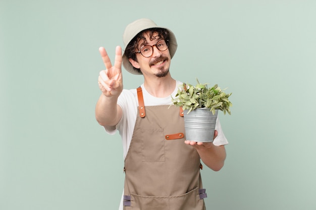 Young farmer man smiling and looking happy, gesturing victory or peace