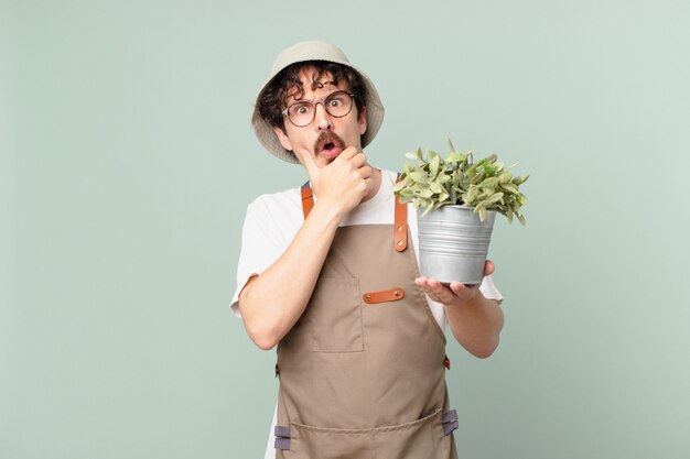 Young farmer man with mouth and eyes wide open and hand on chin