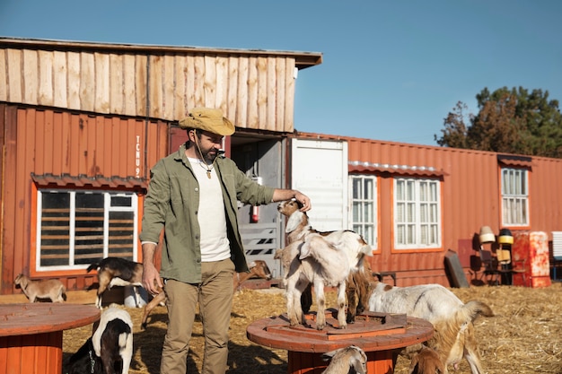 Photo young farmer petting his goats at the farm