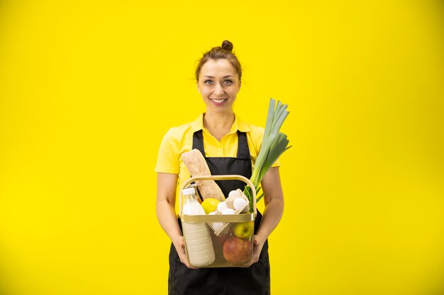 Il giovane agricoltore in uniforme tiene il cestino con generi alimentari, prodotti agricoli di consegna dell'alimento