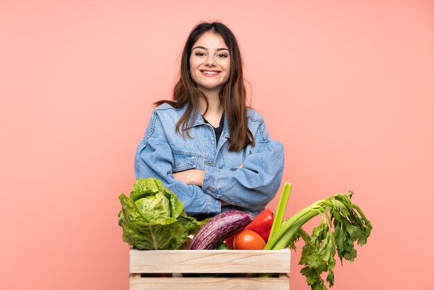 Young farmer woman holding a basket full of fresh vegetables laughing