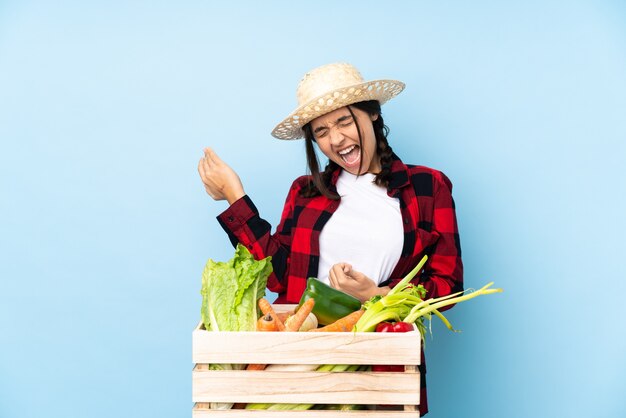 기타 제스처를 만드는 나무 바구니에 신선한 야채를 들고 젊은 농부 여자