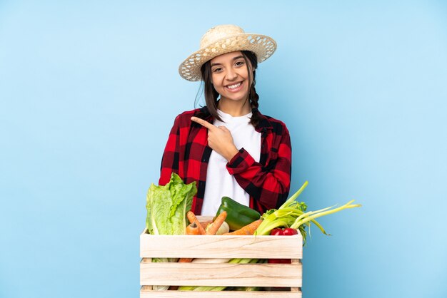 木製のバスケットに新鮮な野菜を保持している若い農家の女性