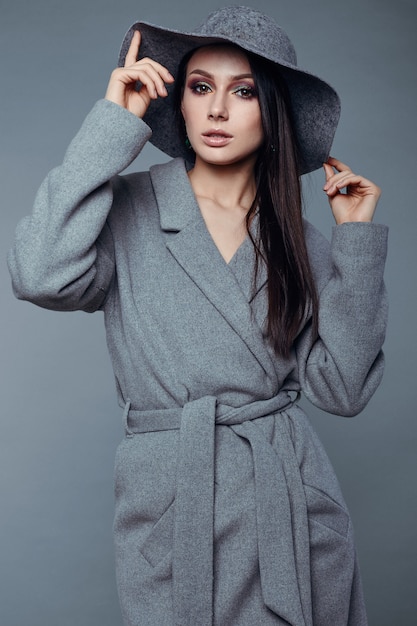 Young fashion brunette woman in gray coat and hat