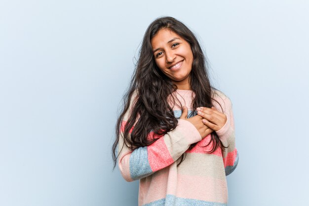 Young fashion indian woman has friendly expression, pressing palm to chest. Love concept.