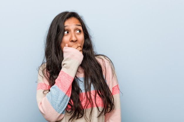 Young fashion indian woman thoughtful looking to a copy space covering mouth with hand.