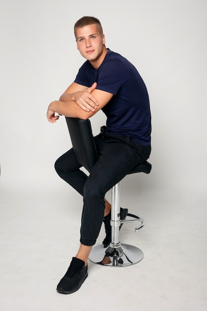 Young fashion man sitting on a chair and posing