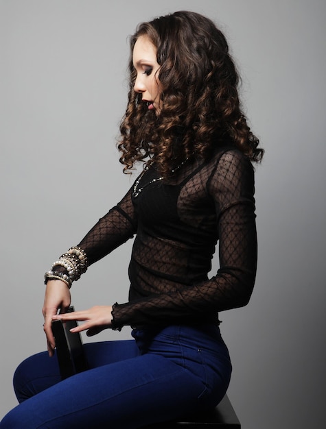 Young fashion model sitting on chair, studio shot