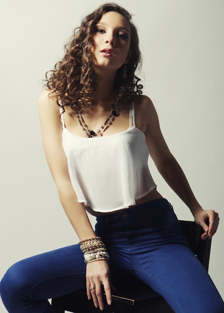 Young fashion model sitting on chair studio shot