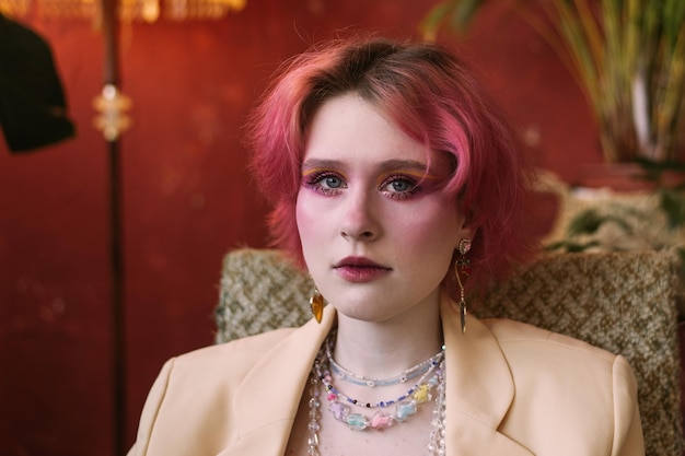 Young fashion stylish woman sitting on chair vintage studio bright make up and colored hair looking ar camera