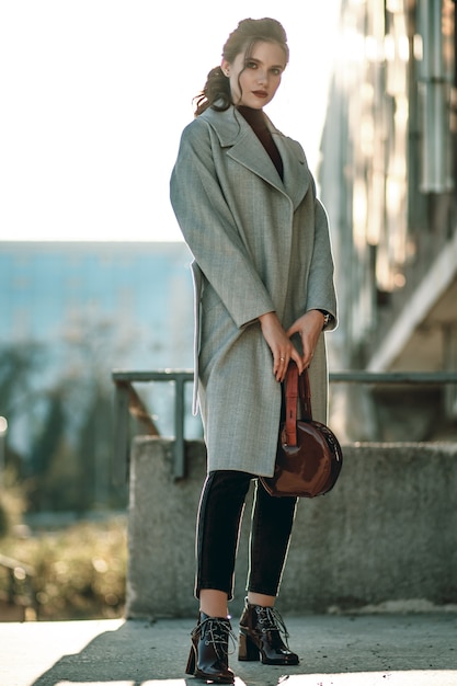 Young fashionable beautiful girl in a long gray coat