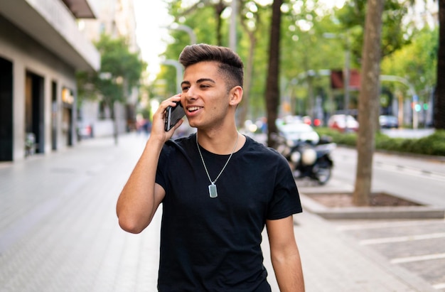 Young fashionable handsome man on the street of modern city talking on a cell phone. Communication concept