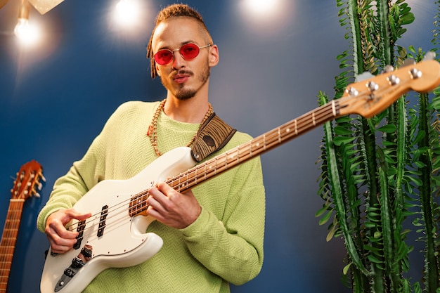 Фото Молодой модный мужчина в розовых очках с радостью играет на гитаре