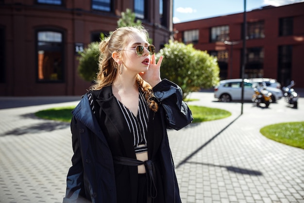 Young and fashionable overweight woman walking around town. Beautiful stylish young red-haired woman enjoys a walk through the autumn city