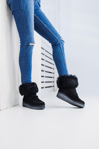 A young fashionable woman in stylish jeans and trendy leather shoes is standing on a white tile Fashionable collection of women's autumn shoes Closeup of female legs in shoes