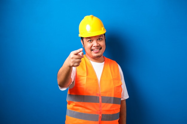 Young fat asian construction worker man wearing safety helmet pointing with finger