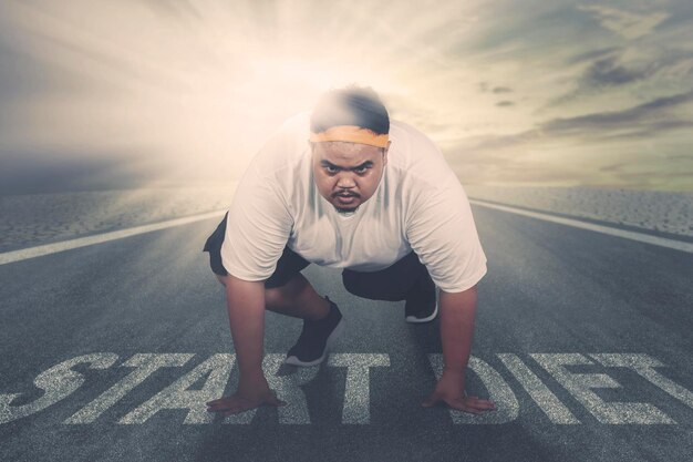 Young fat man kneeling above text of start diet