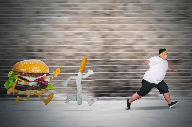 Young fat man runs from cigarette and burger